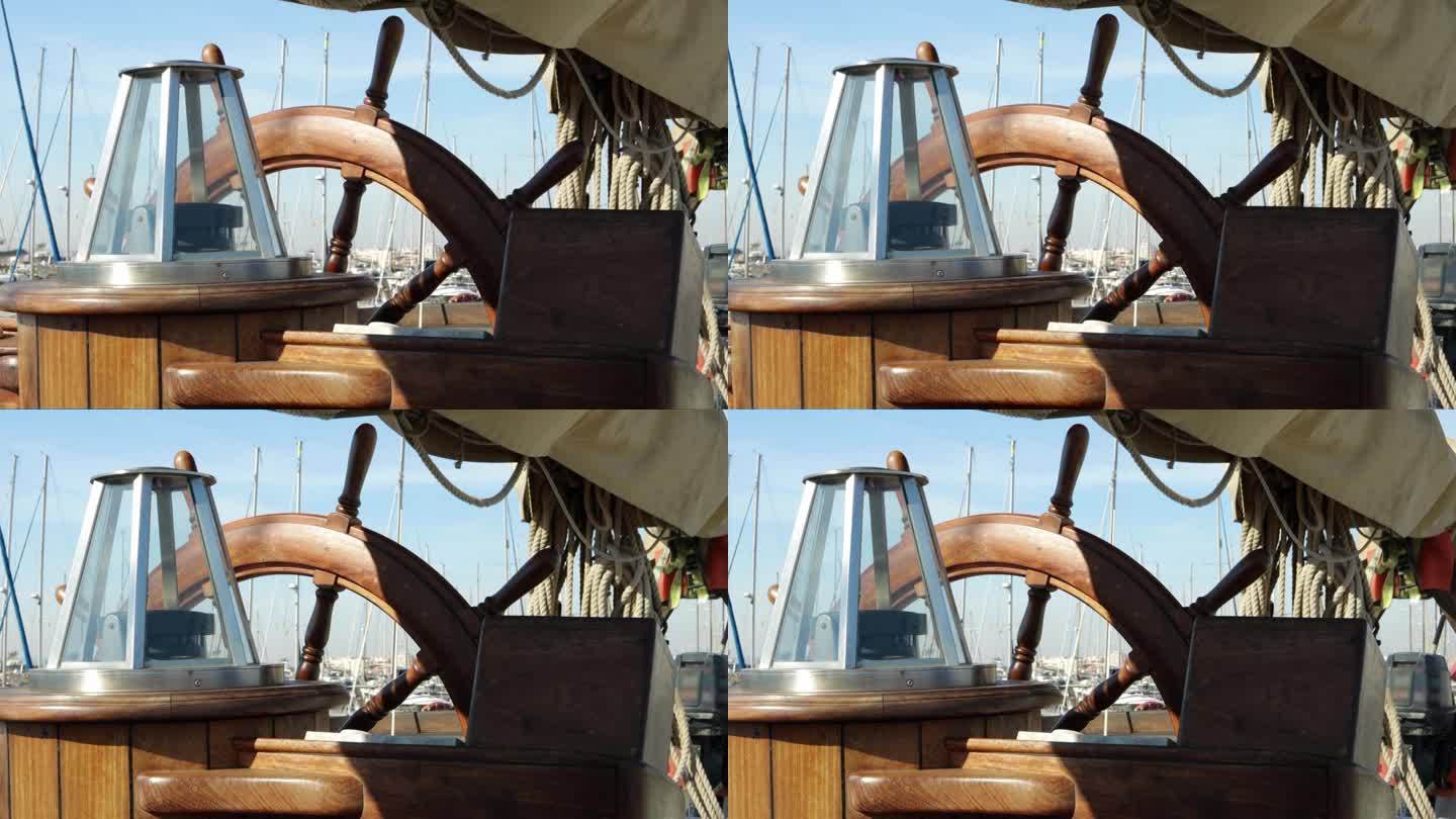 一艘木制古董帆船的方向盘和甲板特写，展示木制部件和配件。带罗经方向盘
