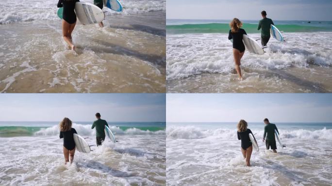 旅行的白人夫妇带着冲浪板在沙滩上跑向海水。男人，女人赶着去赶浪。海边健康的户外休闲。积极的生活方式关