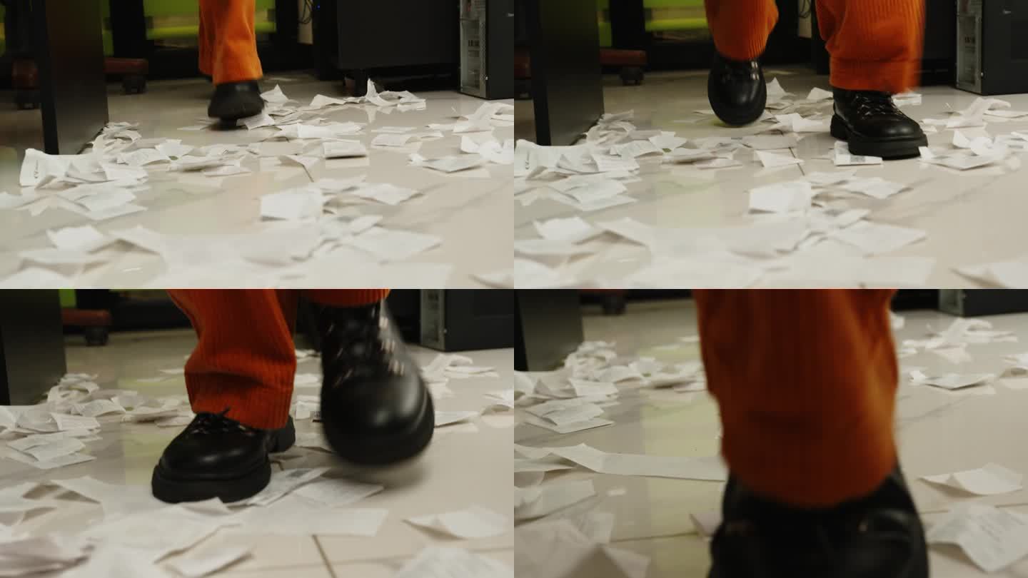 穿着黑鞋和棕色裤子的腿在办公室里翻着散落的文件跑来跑去。脚踩在支票上