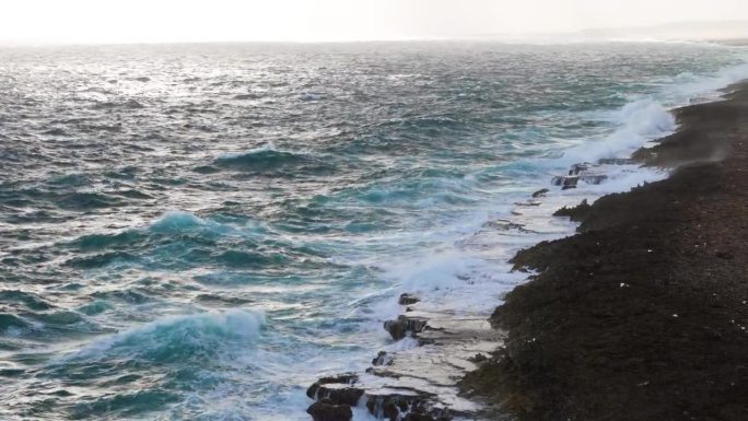 强烈的海浪冲击着岛上被侵蚀的碳酸盐岩，激起阵阵浪花