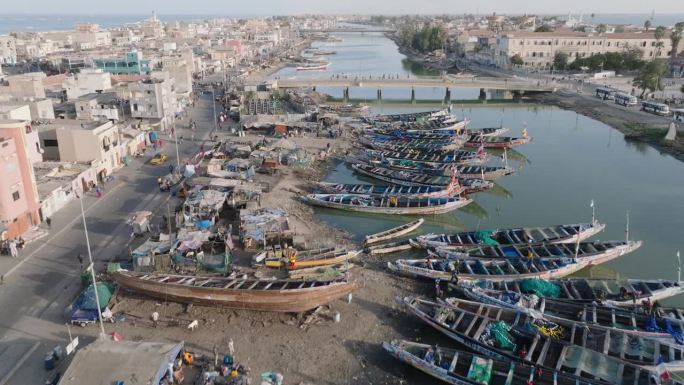 近距离空中飞行。色彩斑斓的独木舟停泊在被污染的塞内加尔河上。塑料污染，塞内加尔圣路易，联合国教科文组