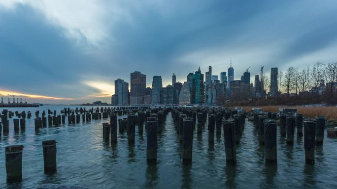 美国布鲁克林大桥公园老一号码头的木桩与纽约金融区的天际线。——间隔拍摄