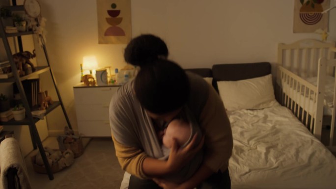 快乐的黑人母亲带着襁褓中的婴儿在卧室里跳舞唱歌