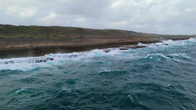 有角度的空中飞行沿海岸下降与强烈的海浪冲击尖锐的岩石