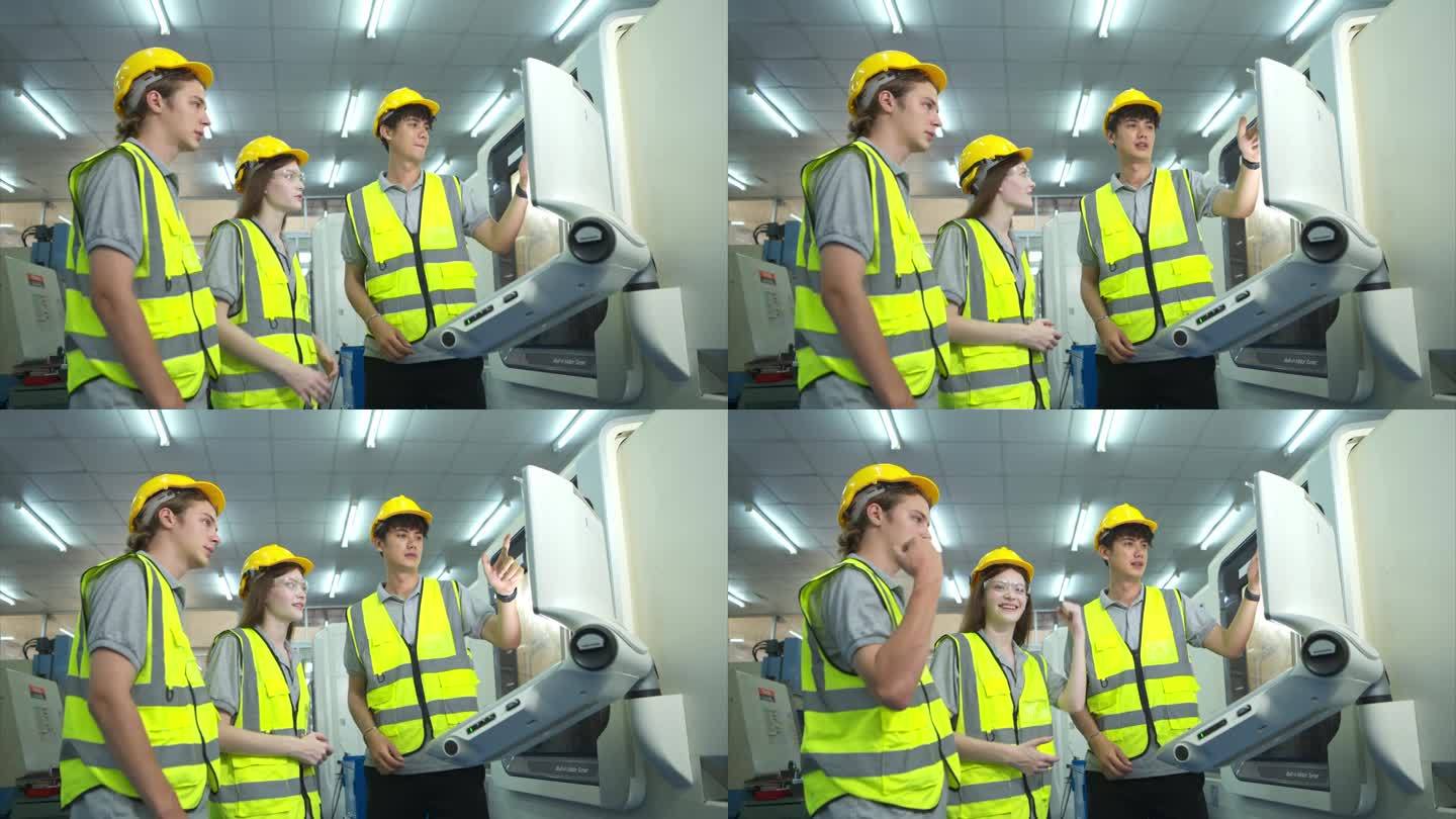 两位年轻的工厂工人都戴着安全帽，看着用于控制生产的电脑屏幕。