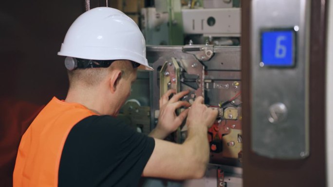 修理工用扳手调整电梯的安全系统。由专业人员安装复杂的设备。维修工程师正在修理电梯，电梯门是开着的。