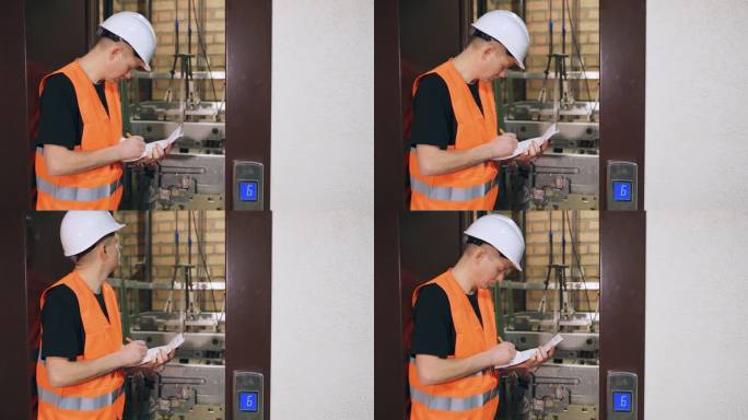 检查电梯部件，复杂的现代电梯设备的质量。男工人检查电梯，门是开着的。多层住宅楼的电梯站