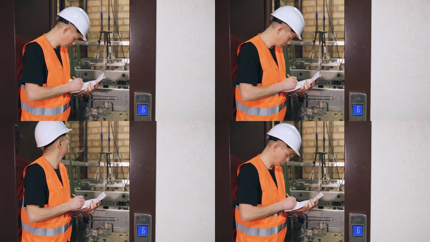 检查电梯部件，复杂的现代电梯设备的质量。男工人检查电梯，门是开着的。多层住宅楼的电梯站