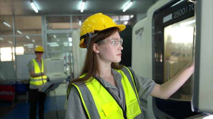 图为一名戴着安全帽的女工看着用于控制生产的电脑屏幕。