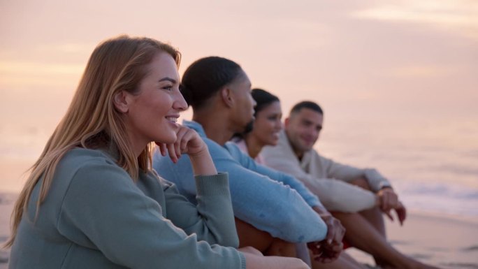 度假时穿着休闲装的年轻女子和朋友坐在沙滩上一起看日出