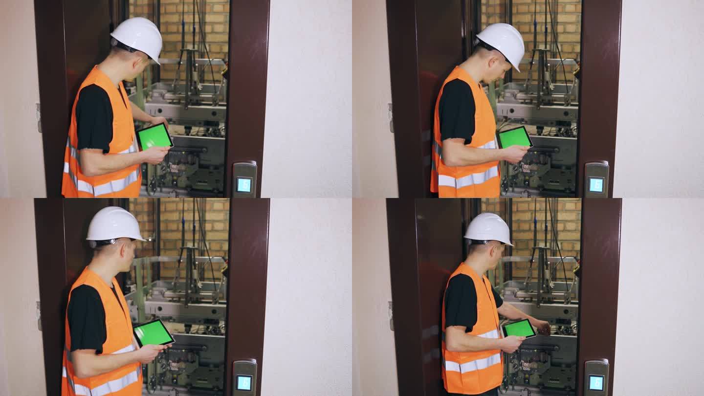 工程师使用数字平板电脑控制电梯安全系统。维修工程师正在修理电梯，电梯门是开着的。