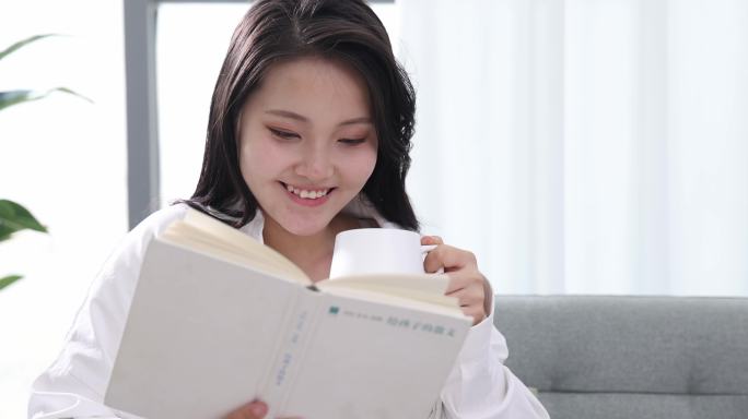 一位年轻女士在家看书喝咖啡