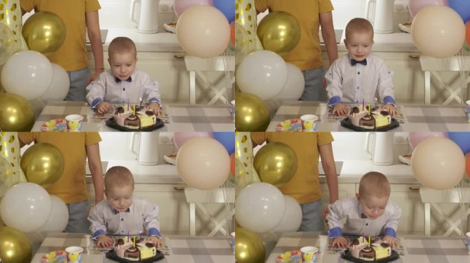 3岁的孩子用蛋糕庆祝生日。活泼可爱的小男孩吹灭了生日蛋糕上的蜡烛。在家里举行家庭生日聚会。