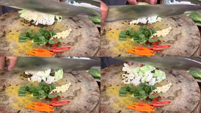 厨师熟练地用一把大刀在木制砧板上切碎新鲜的卷心菜，准备做传统的亚洲炒菜