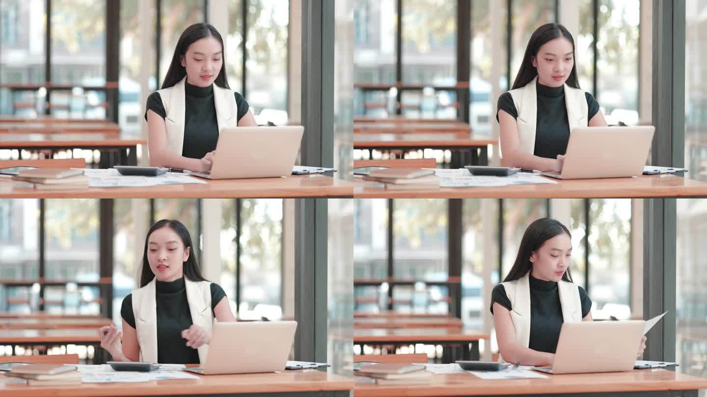 年轻的女商人在联合办公空间用她的笔记本电脑和打印的图表检查数据