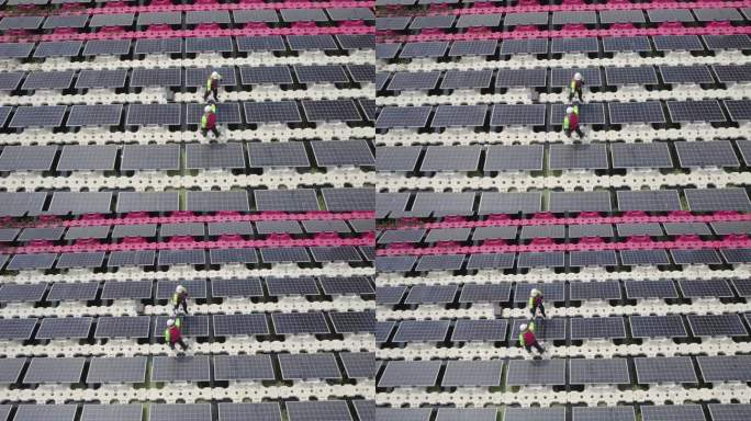 俯视图两名技术工人站在太阳能电池板系统的基座上，为工作的顺利进行而握手。