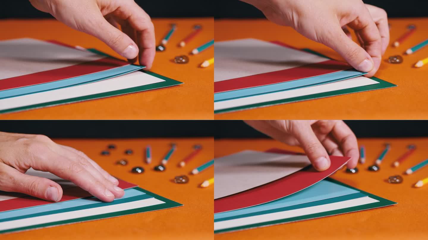 女性的手在橙色的背景上铺着五颜六色的纸板