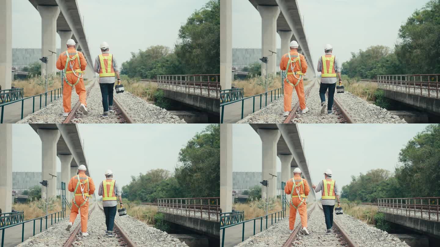 两名美国成年高级铁路工程师，头戴安全帽，身穿防护服，在铁路轨道上行走，在车辆段观察两条轨道的规定距离