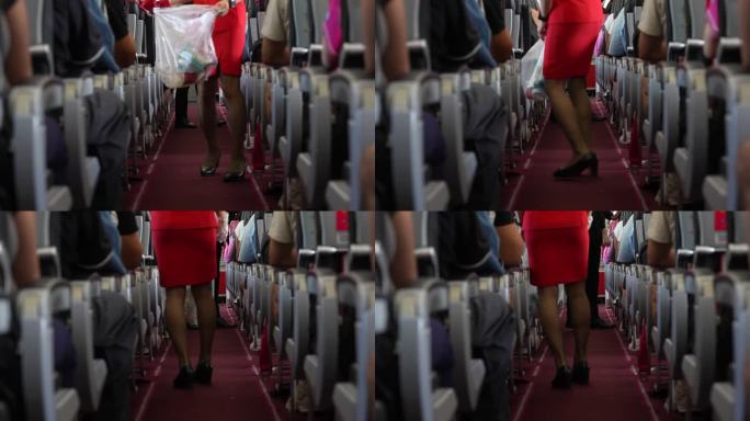 中景:身穿红色套装的空姐或空乘手持不透明垃圾袋