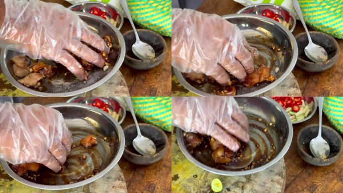 一名厨师用戴着手套的手将酱油、香料和调味料混合到生鸡肉中，同时烹饪传统的巴厘岛沙茶鸡肉串。