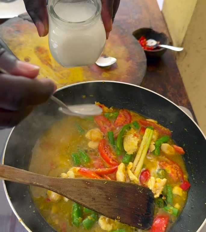 将椰奶加入到美味的印尼鸡肉和蔬菜椰子咖喱中，在煤气灶上煨煮