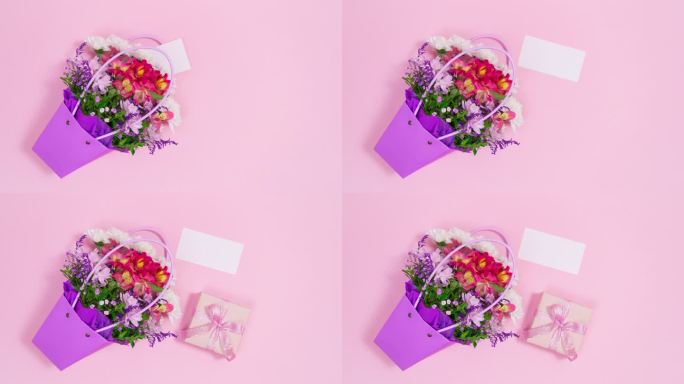 一束鲜花在紫色的袋子连同白色的卡片和礼盒出现在粉红色的背景。