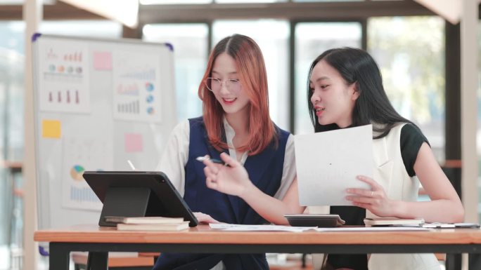 年轻的女商人在项目办公空间用平板电脑和打印图表一起工作和头脑风暴。