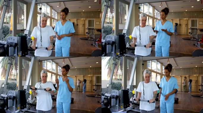 女性黑人治疗师解释如何在物理治疗中正确使用机器锻炼手臂-附带治疗师和患者作为背景