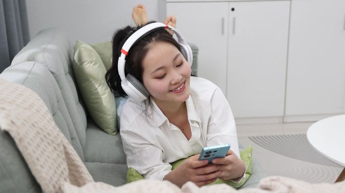 年轻女士在家玩手机听音乐