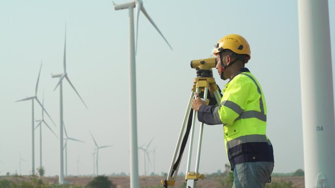 在风力发电厂工作的4K男工程师使用测量设备水平经纬仪
