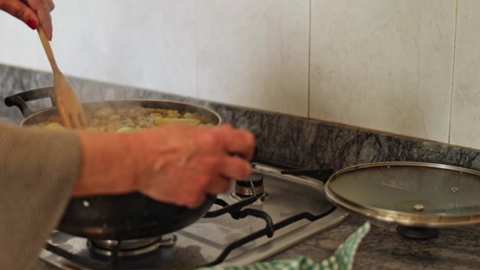 妇人正在炉子上的锅里搅拌炖菜