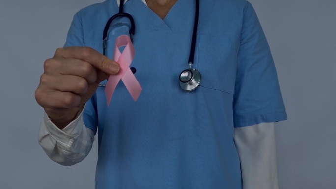 医生拿着女性乳房和粉色结的人工模型