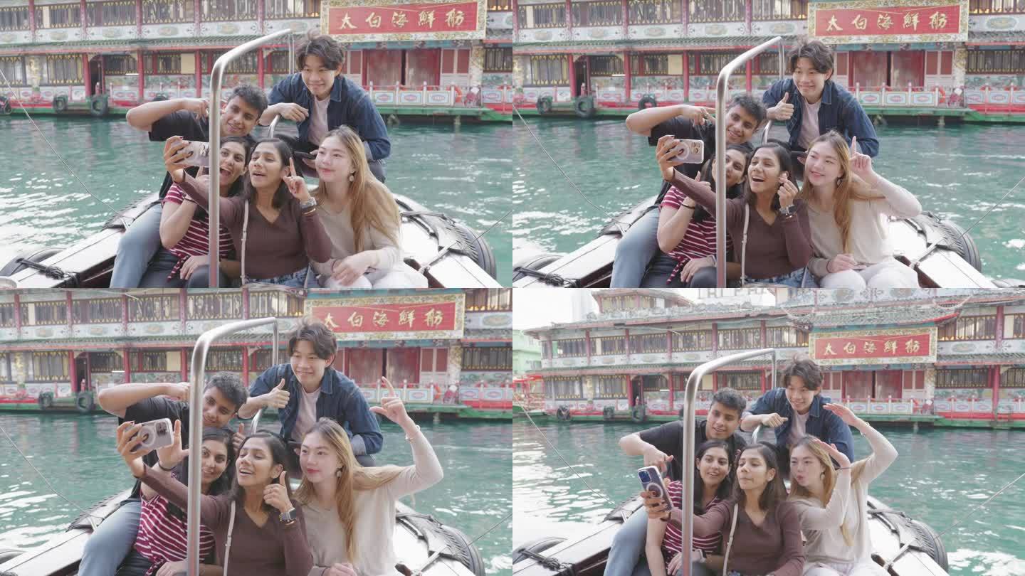 一群亚洲朋友在香港一间水上餐厅前的船上自拍