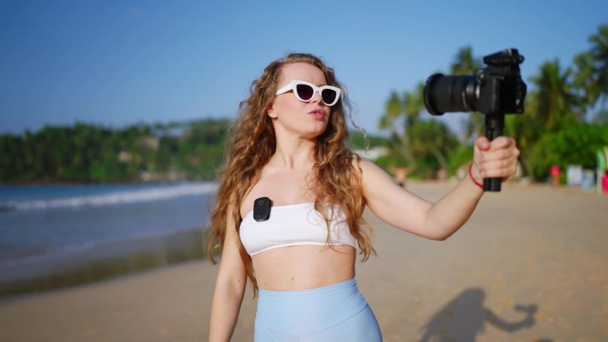 内容创作者用高质量的数码单反拍摄海滩视频，阳光照亮了热带环境。一名女子使用无线麦克风，用旅行日志吸引