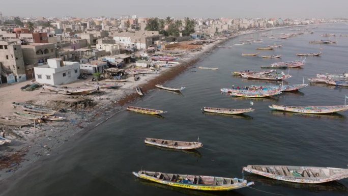 空中飞行。色彩斑斓的独木舟停泊在被污染的塞内加尔河上。塞内加尔圣路易，联合国教科文组织世界遗产地，塑