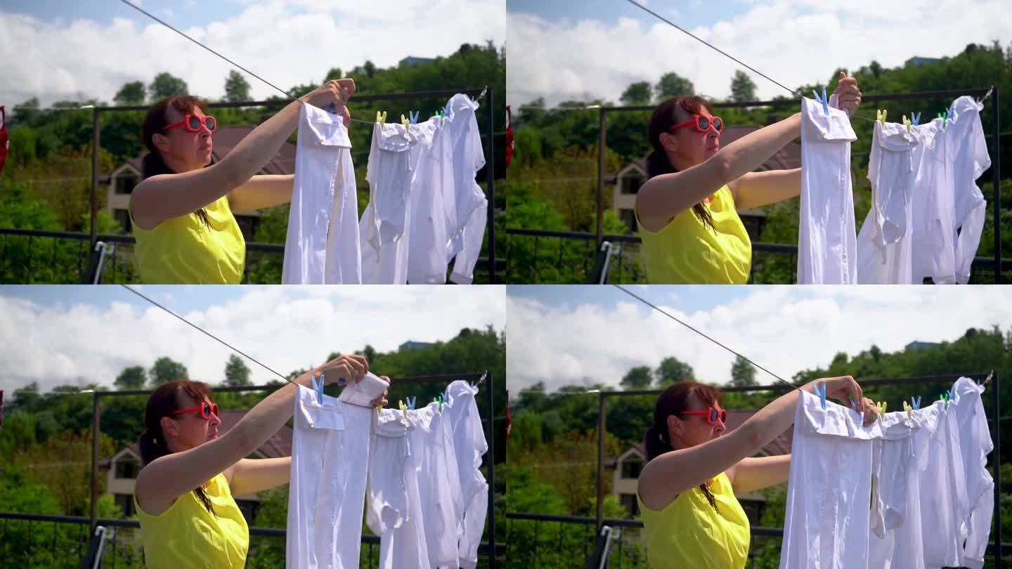 一个女人把洗好的衣服挂在晒衣绳上。