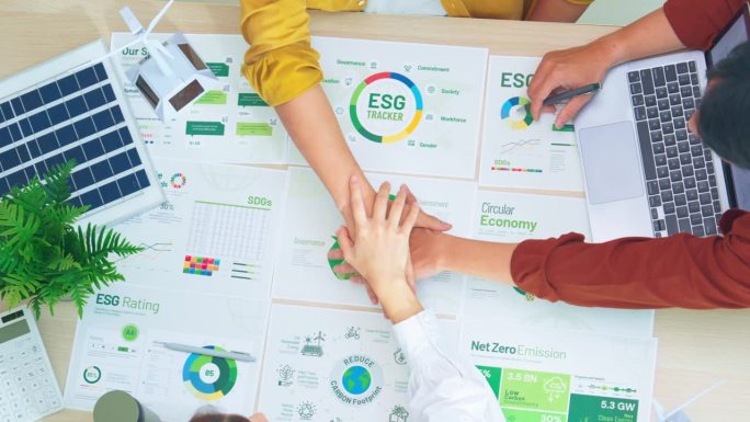 一群多元化的商业人士加入手拉手的团队团结，ESG会议环境，社会和治理，在办公室讨论可再生能源风力涡轮