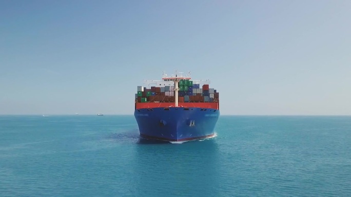 货船船头和满是集装箱的前甲板正在接近。集装箱船在平静的水面上行驶时的空中正面视图。