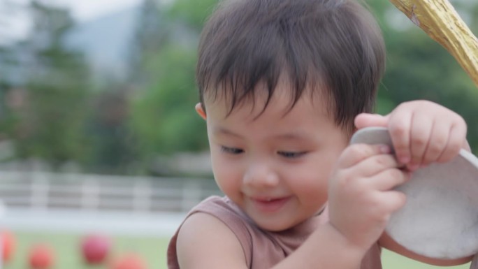一个可爱的亚洲小男孩的特写脸在公园外面玩耍。面部表情和眼神探索。天真可爱的小婴儿。