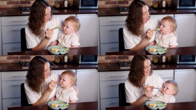 快乐的爱心妈妈在厨房用勺子喂她的宝宝。健康饮食，断奶，补充喂养。宝宝第一次吃固体食物