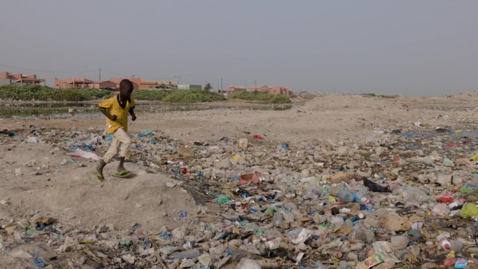 年轻的非洲黑人男孩在可怕的塑料污染中玩耍