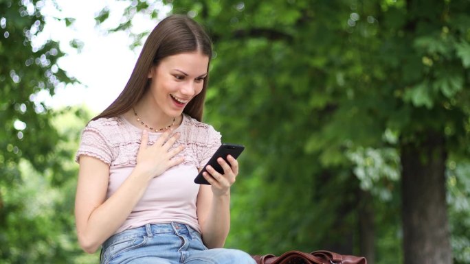 非常高兴的女人通过智能手机读到好消息