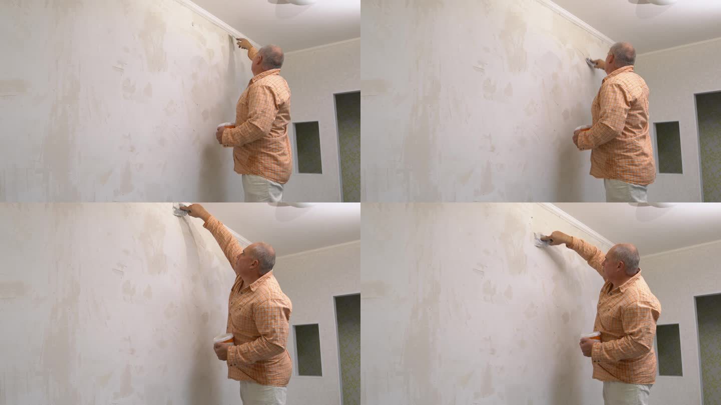 一个人把腻子涂在墙上，用抹刀把腻子抹平。