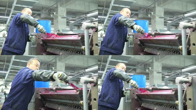 印刷厂男工人在给滚轮抹油膜
