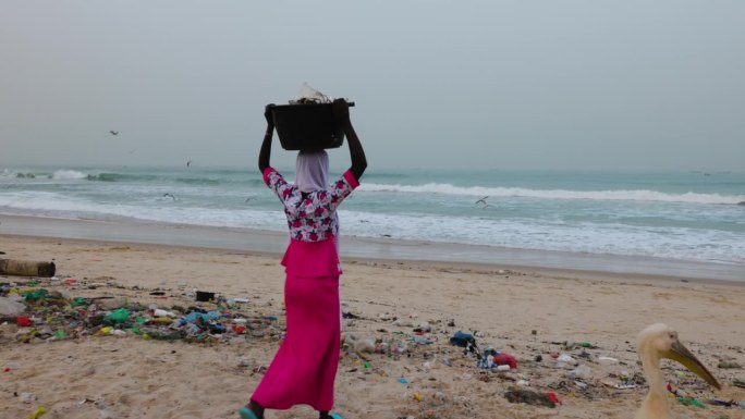 非洲黑人妇女在海边倾倒垃圾。可怕的塑料污染。