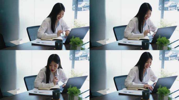 微笑的亚洲女商人在明亮的办公空间里用笔记本电脑工作