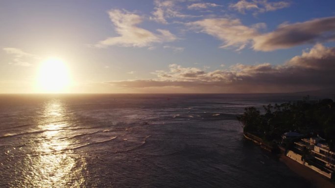 夏威夷瓦胡岛檀香山附近，太平洋上明亮的白色太阳缓缓落下，天上的白云映衬着蓝天