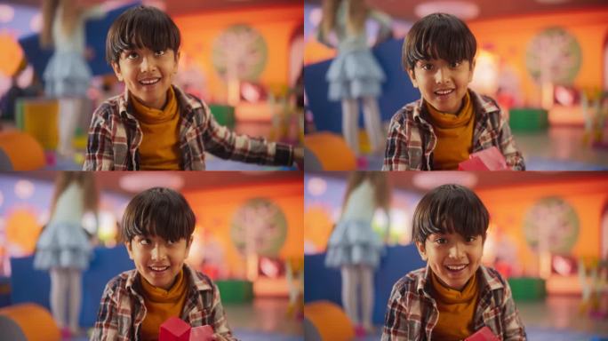 一个可爱的印度小男孩的肖像，看着相机，微笑着。南亚儿童在幼儿园玩积木。孩子们在现代日托中心学习和玩耍