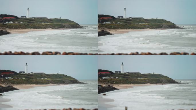 丹麦赫茨哈尔斯海岸的灯塔和露营地。海浪在沙滩上缓缓地翻滚。