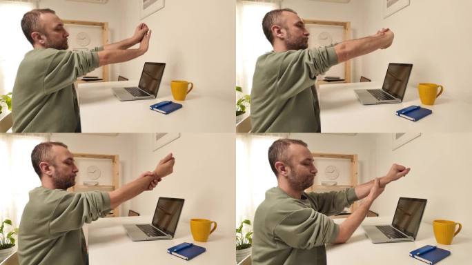 一名男子一边用笔记本电脑工作，一边伸展着疼痛的双手和手臂。